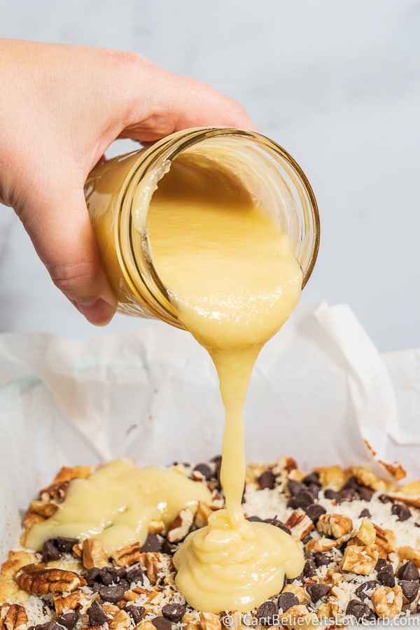 Pouring condensed milk on Keto Magic Cookie Bars