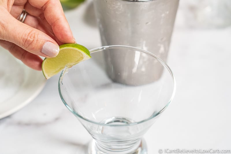 squeezing lime on rim of glass for margarita