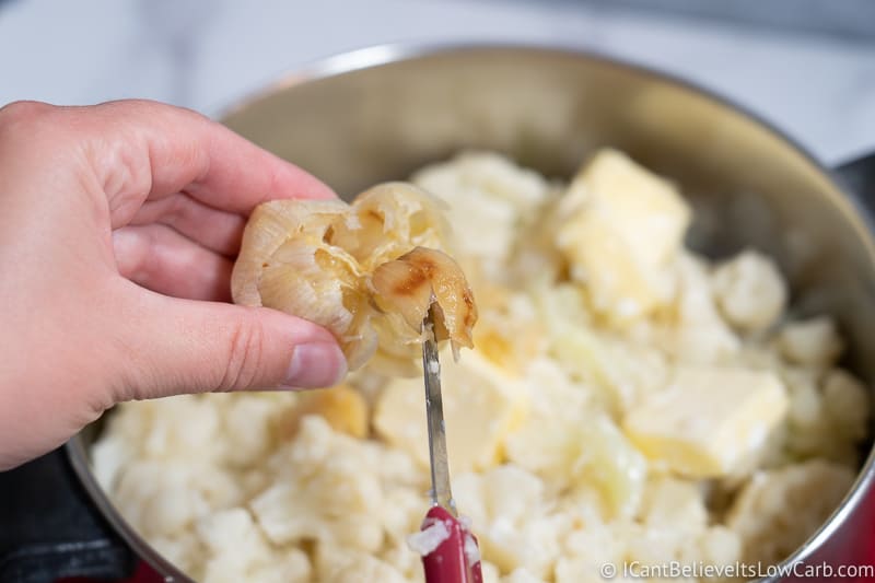adding garlic to Cauliflower Mashed Potatoes