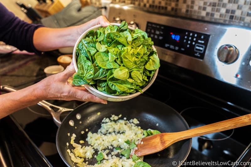 pouring Spinach in pan to cook