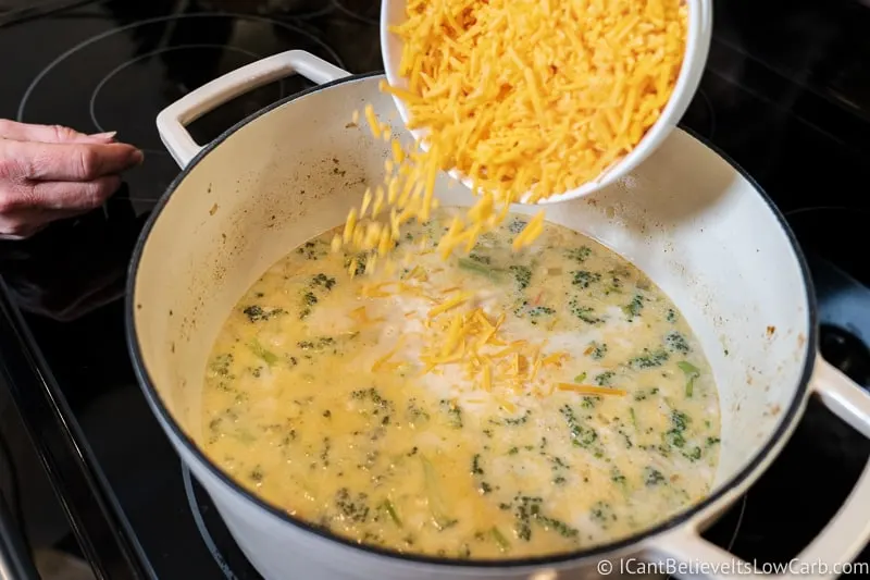 adding cheese to Keto Broccoli Cheddar Soup