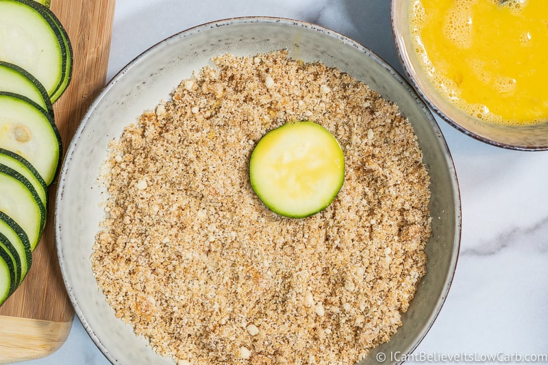 Keto Fried Zucchini dipping in breadcrumbs