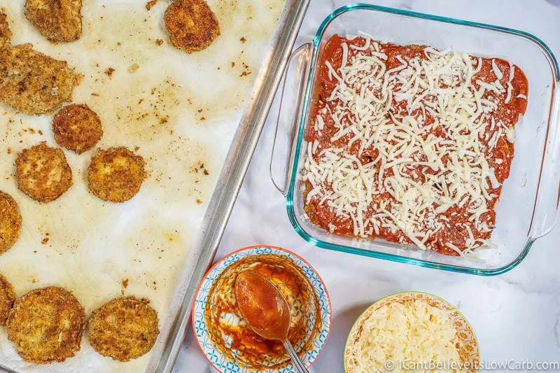 assembling Keto Eggplant Parmesan in baking dish with cheese