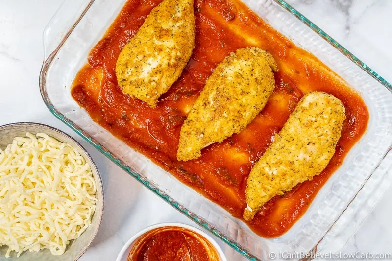 almond flour breaded chicken in pan with tomato sauce