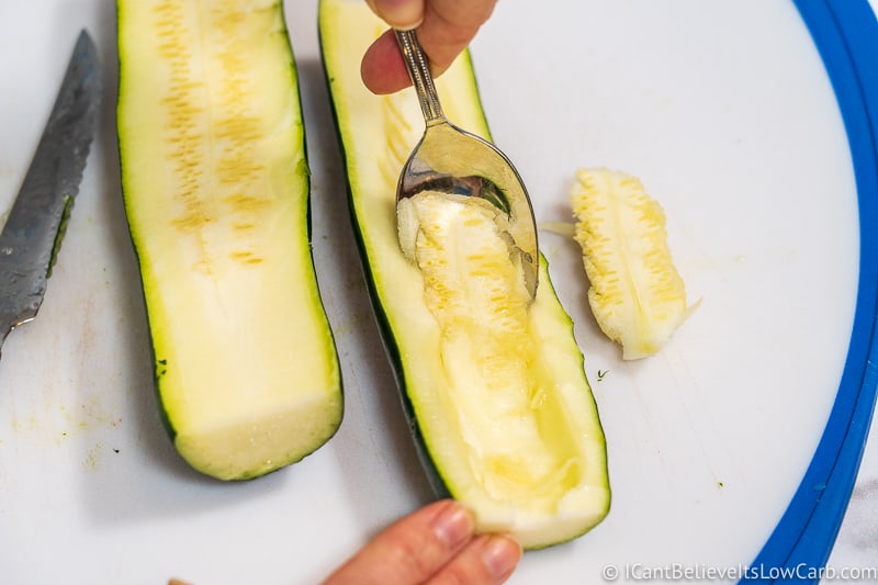 scooping out zucchini flesh with a spoon