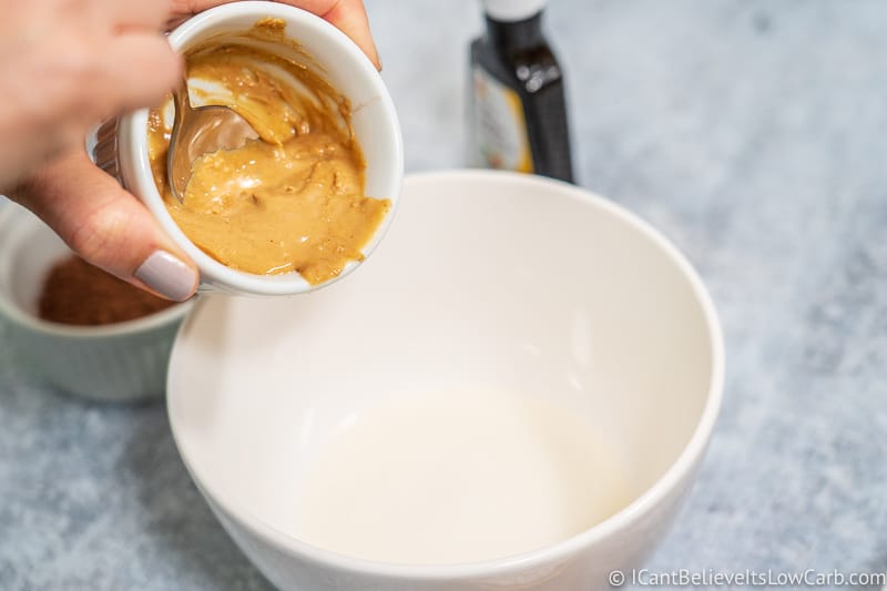 scooping natural peanut butter in bowl with coconut oil