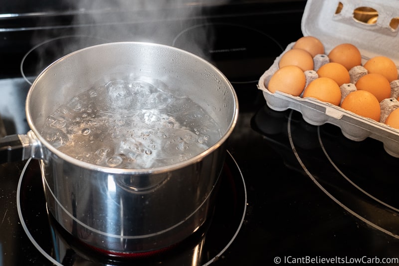 Boiling water on the stove with Eggs in a carton
