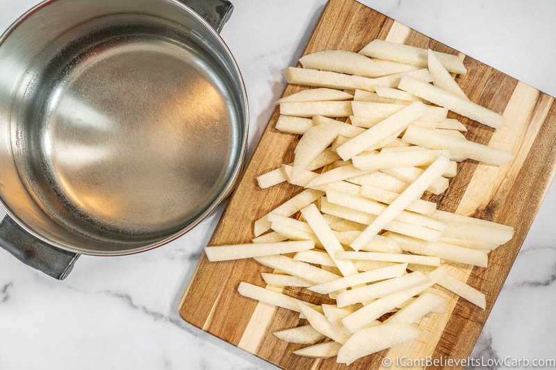 uncooked Jicama Fries on board with empty pot