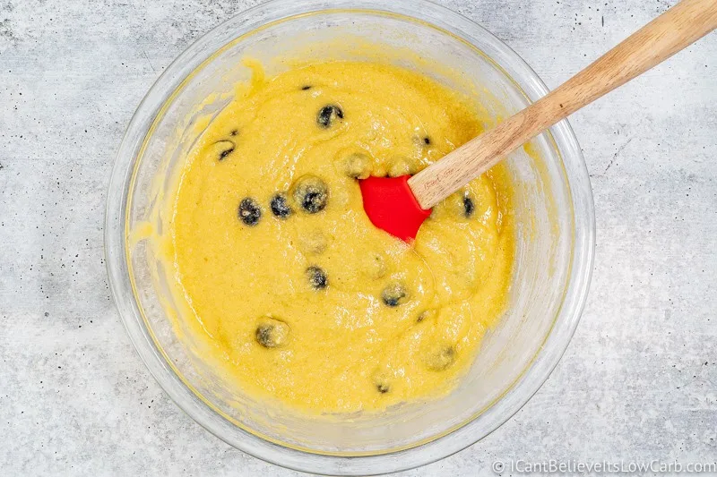 mixing blueberries into Keto Blueberry Muffin batter