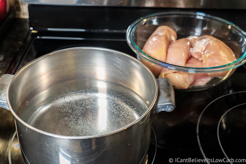 pot of water on the stove and bowl of raw chicken