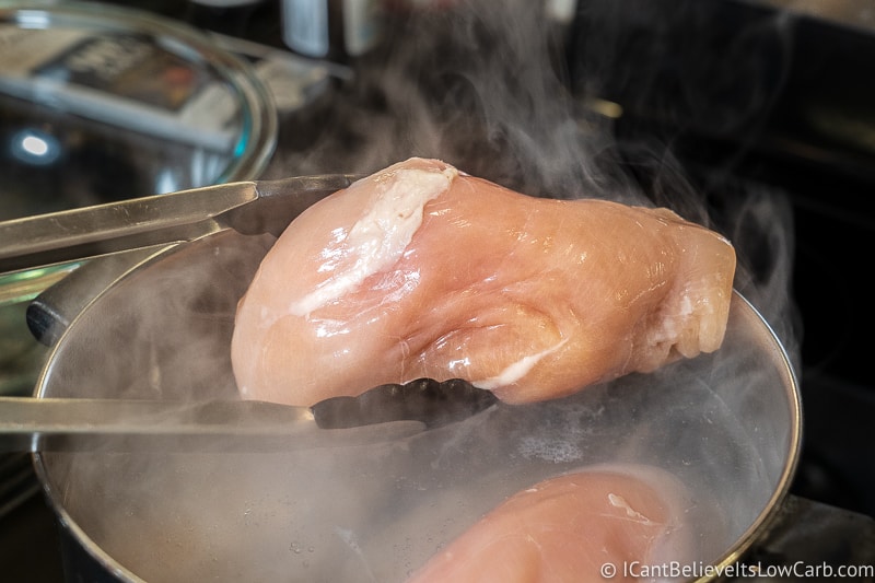 putting Chicken into boiling water to poach