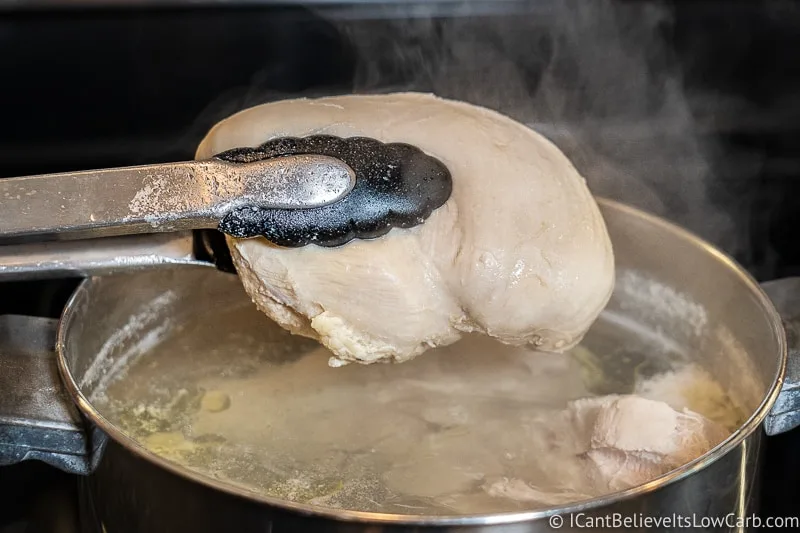 lifting poached Chicken out of the water with tongs