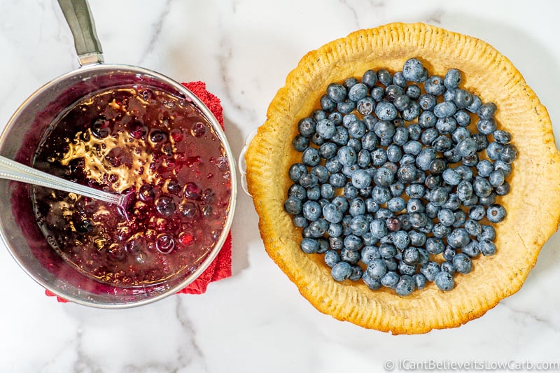 almond flour pie crust with blueberries and pot of sugar free blueberry filling