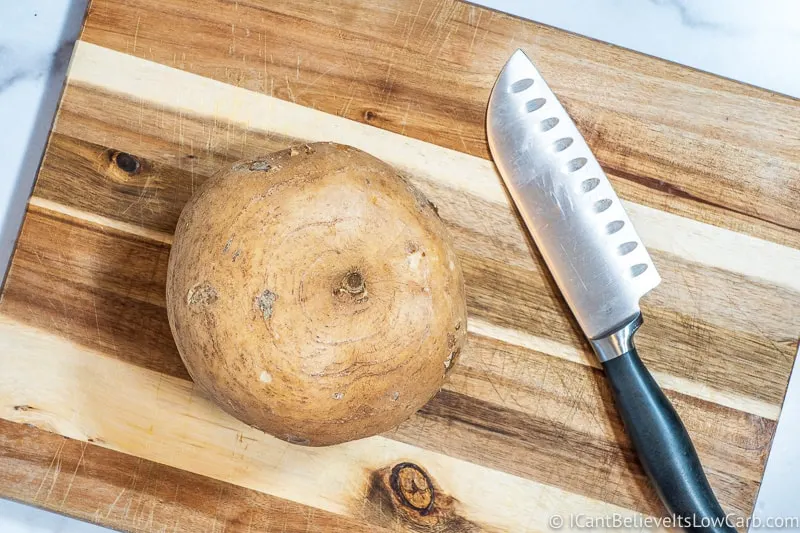 raw jicama on cutting board with knife