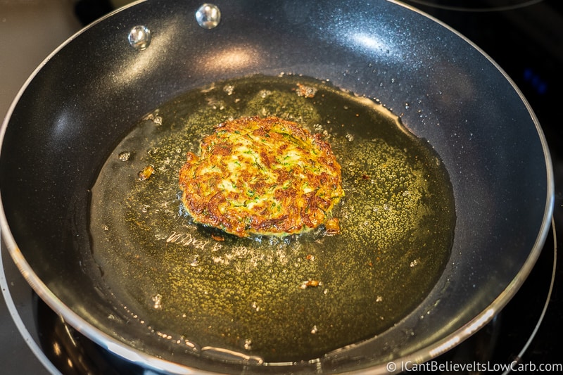 One Keto Zucchini Fritter frying in a pan