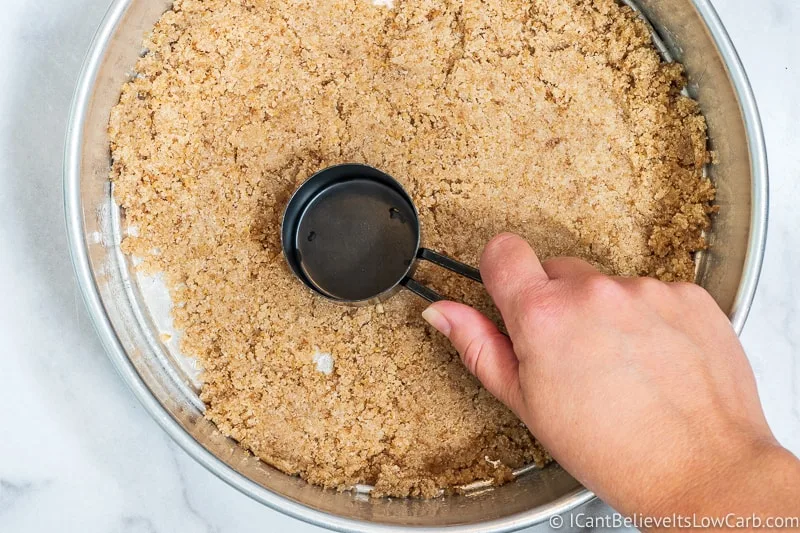 Pressing almond flour cheesecake crust into springform pan