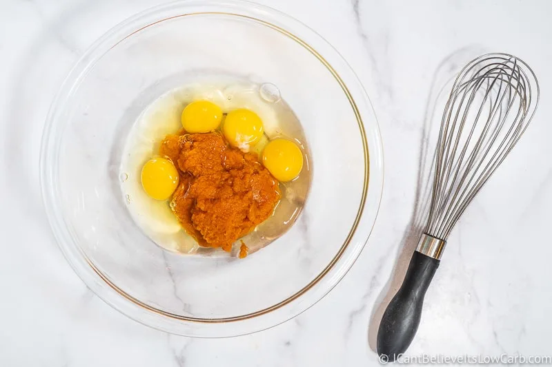 adding eggs to pumpkin puree in a bowl