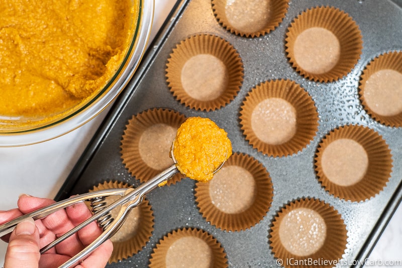 Scooping Keto Pumpkin Muffin mixture into liners