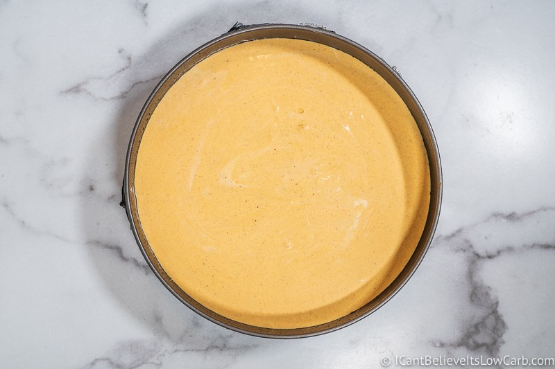 Keto Pumpkin Cheesecake filling poured on top of the crust in springform pan