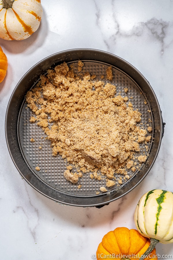 Pouring Pumpkin Cheesecake crust ingredients into pan
