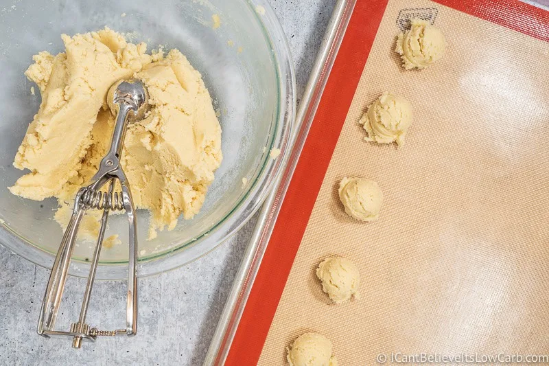 Scooping out Cream Cheese Cookie dough on baking tray
