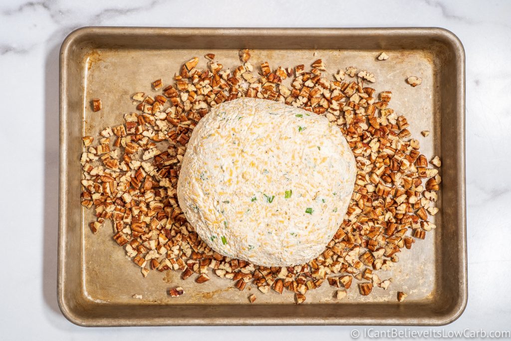 Rolling Cheese Ball on a metal tray with pecans