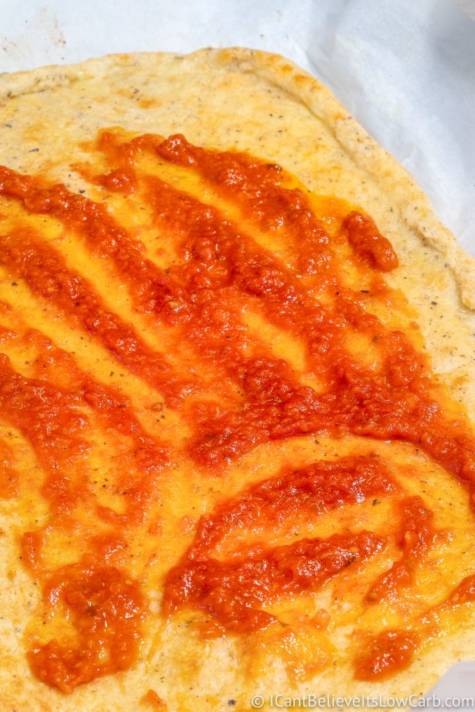 spreading tomato sauce onto Keto Crust
