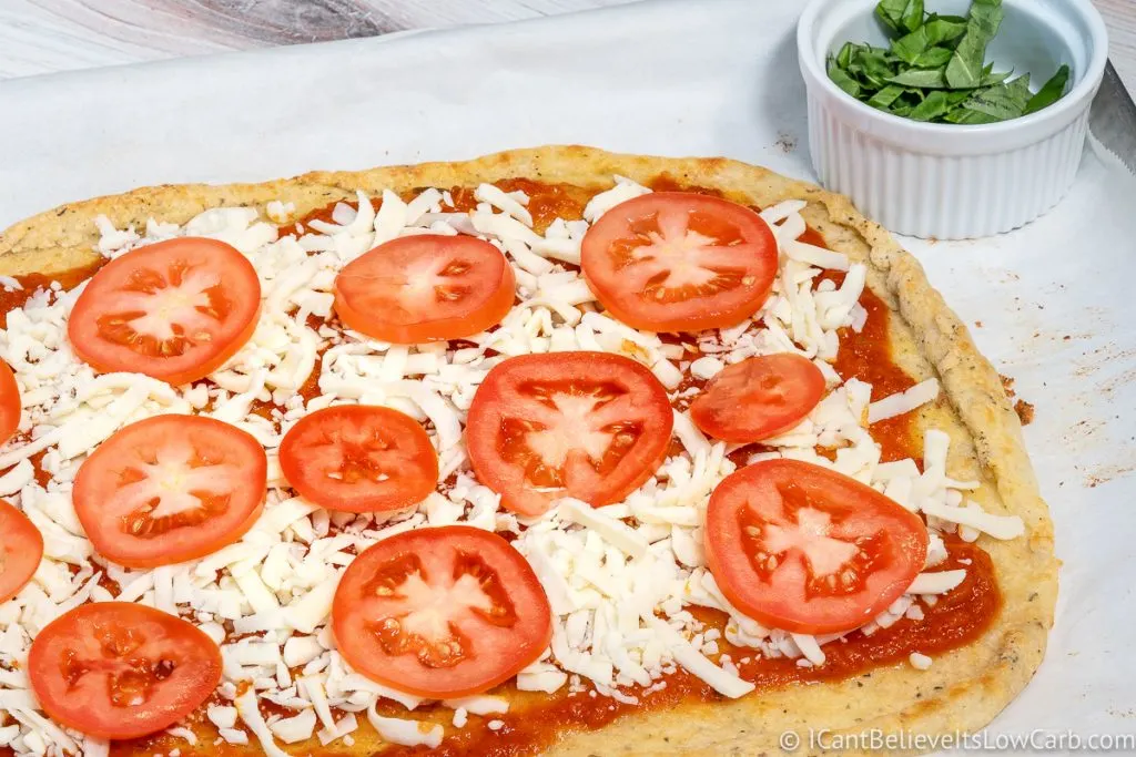adding fresh tomatoes on Low Carb pizza
