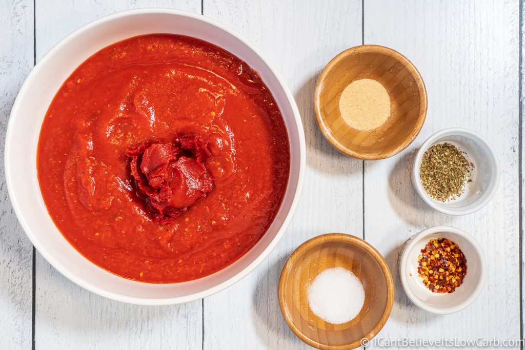 Adding tomato paste to crushed tomatoes and other ingredients