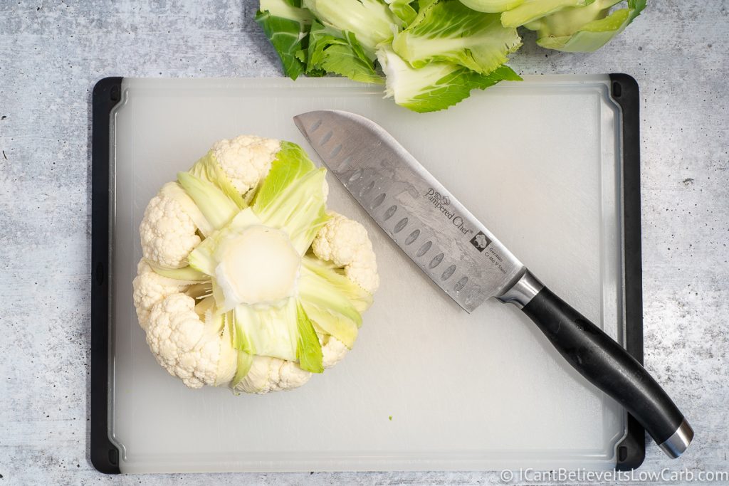one head of Cauliflower on a cutting board with a knife