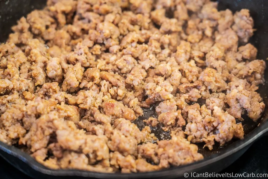 spicy sausage frying in cast iron pan