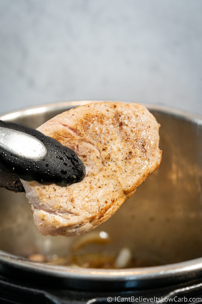 Lowering the pork chops into the Instant Pot
