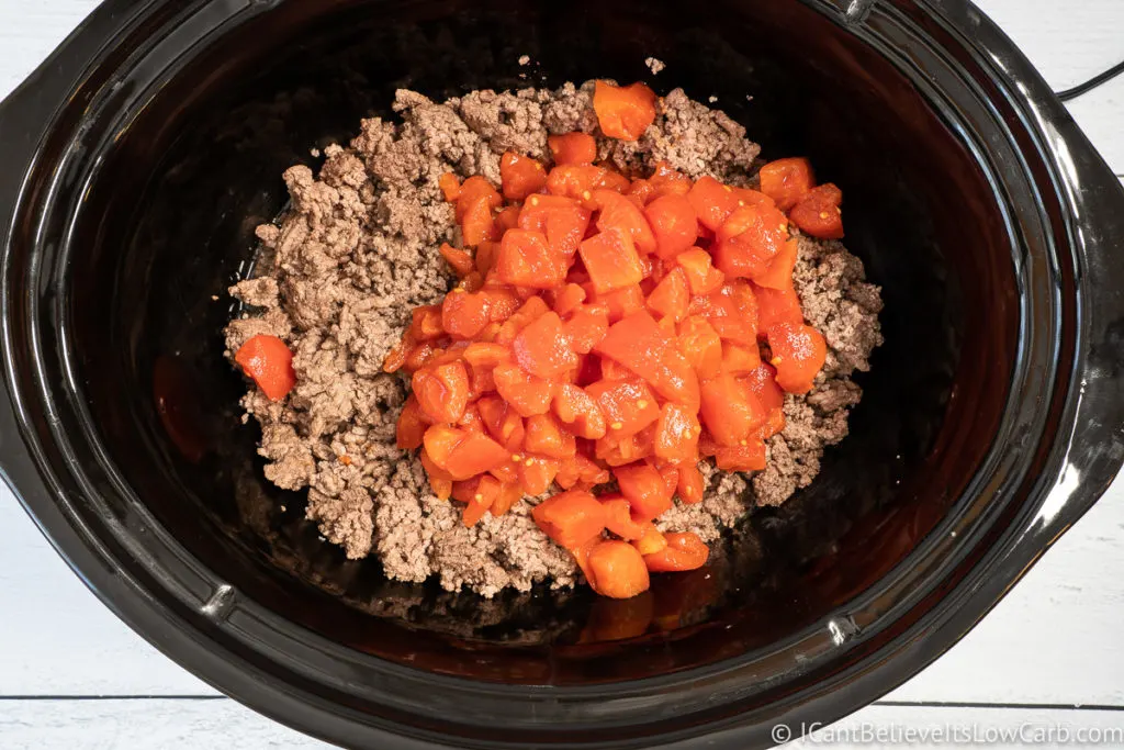 adding ground beef and tomatoes to slow cooker