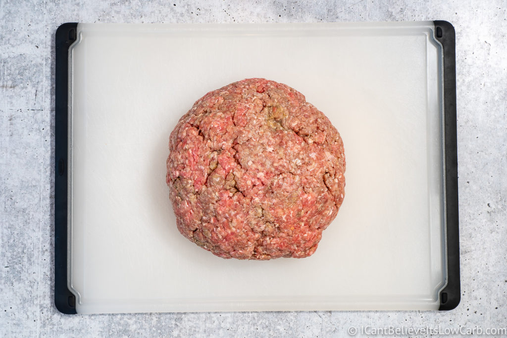 Hamburger meat in a ball on a cutting board