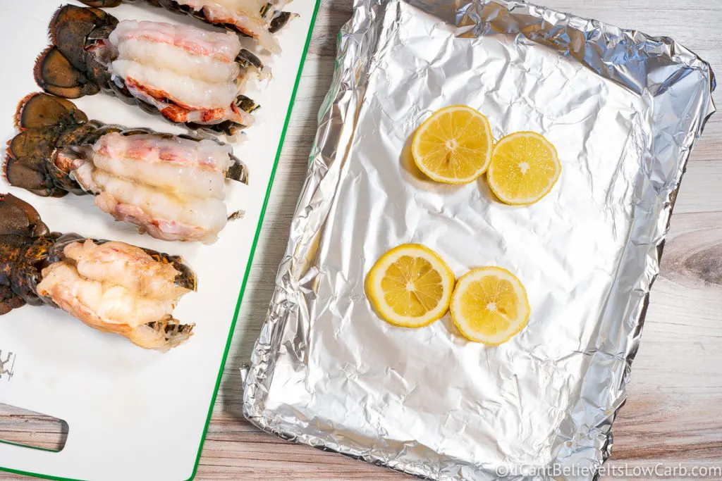 Lobster Tails on cutting board and sheet pan with lemon slices