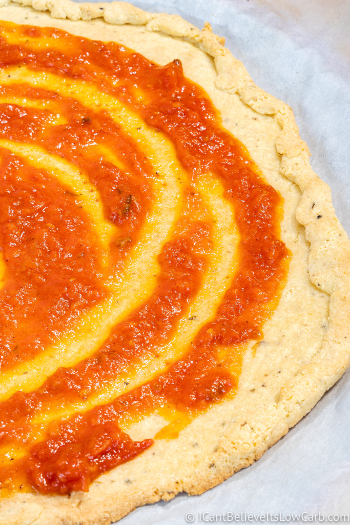 Putting tomato sauce on Almond Flour Pizza Crust