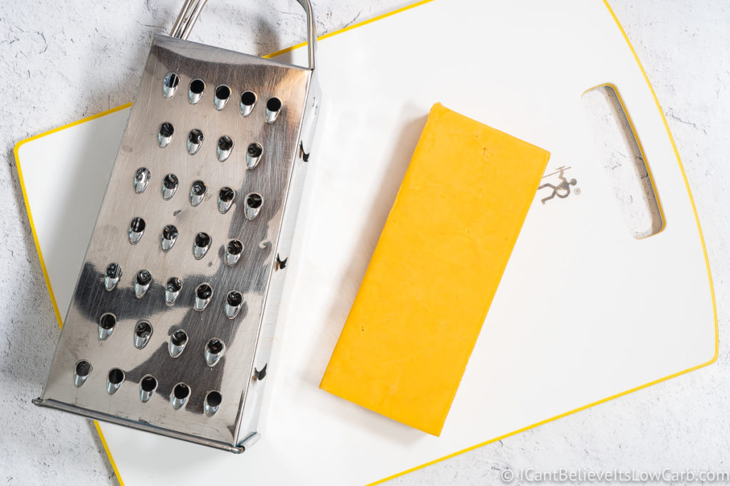 block of cheddar cheese on cutting board