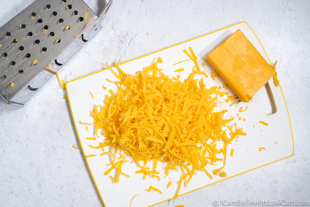 shredded cheddar cheese on a cutting board