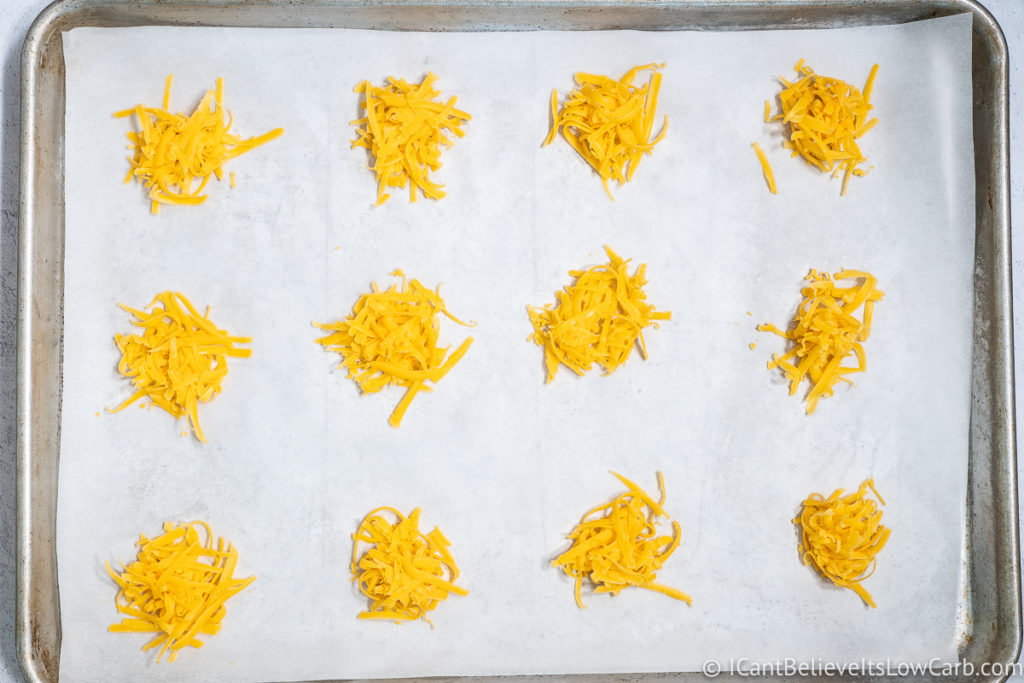 baking sheet with 12 scoops of shredded cheddar cheese