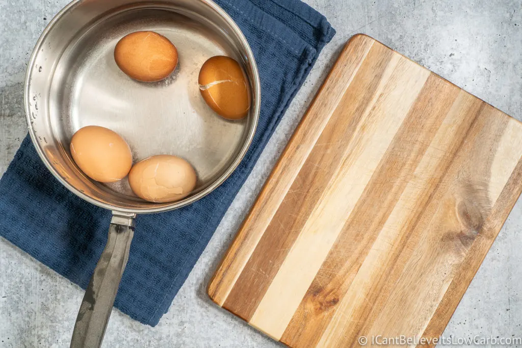 Soft Boiled Eggs in a pan in water and a cutting board