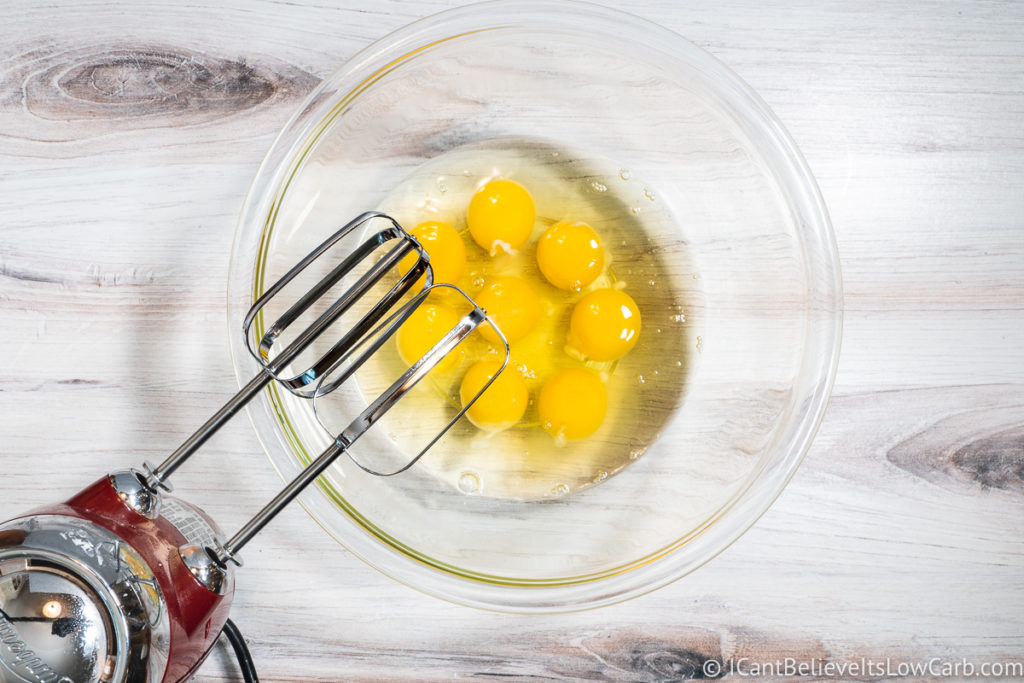 adding eggs to a glass bowl
