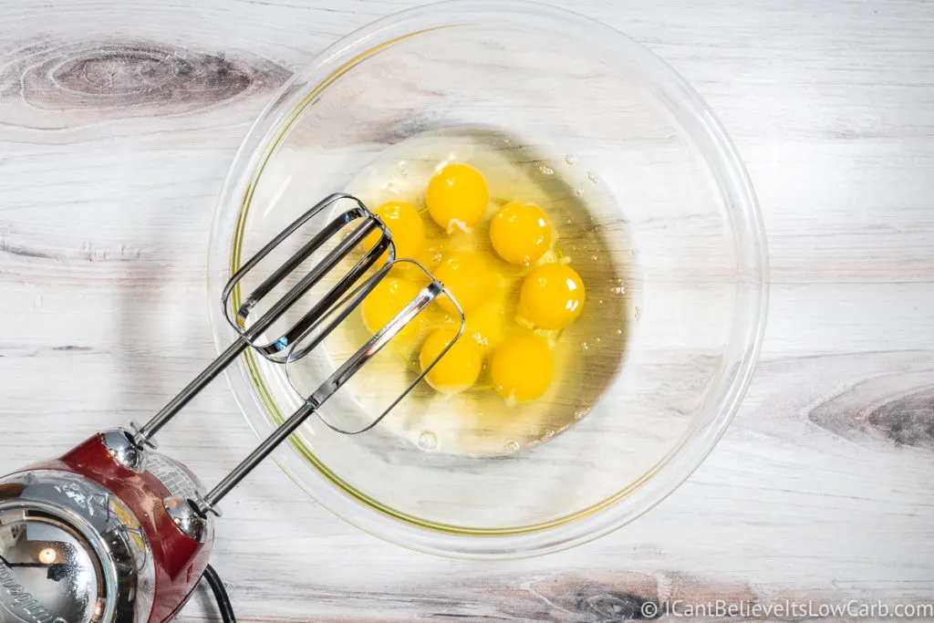 adding eggs to a glass bowl