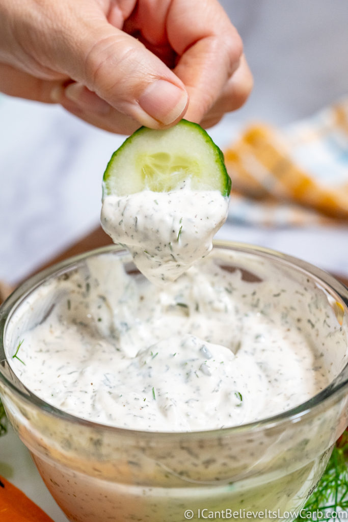 Dipping cucumber in Keto Ranch Dressing