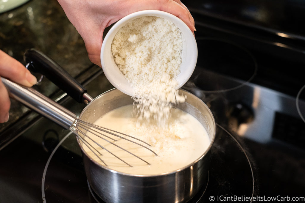 adding cheese to the Alfredo sauce