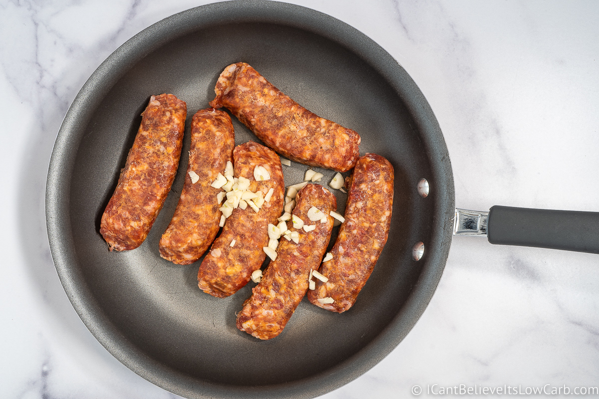 adding garlic to the sausage in a pan